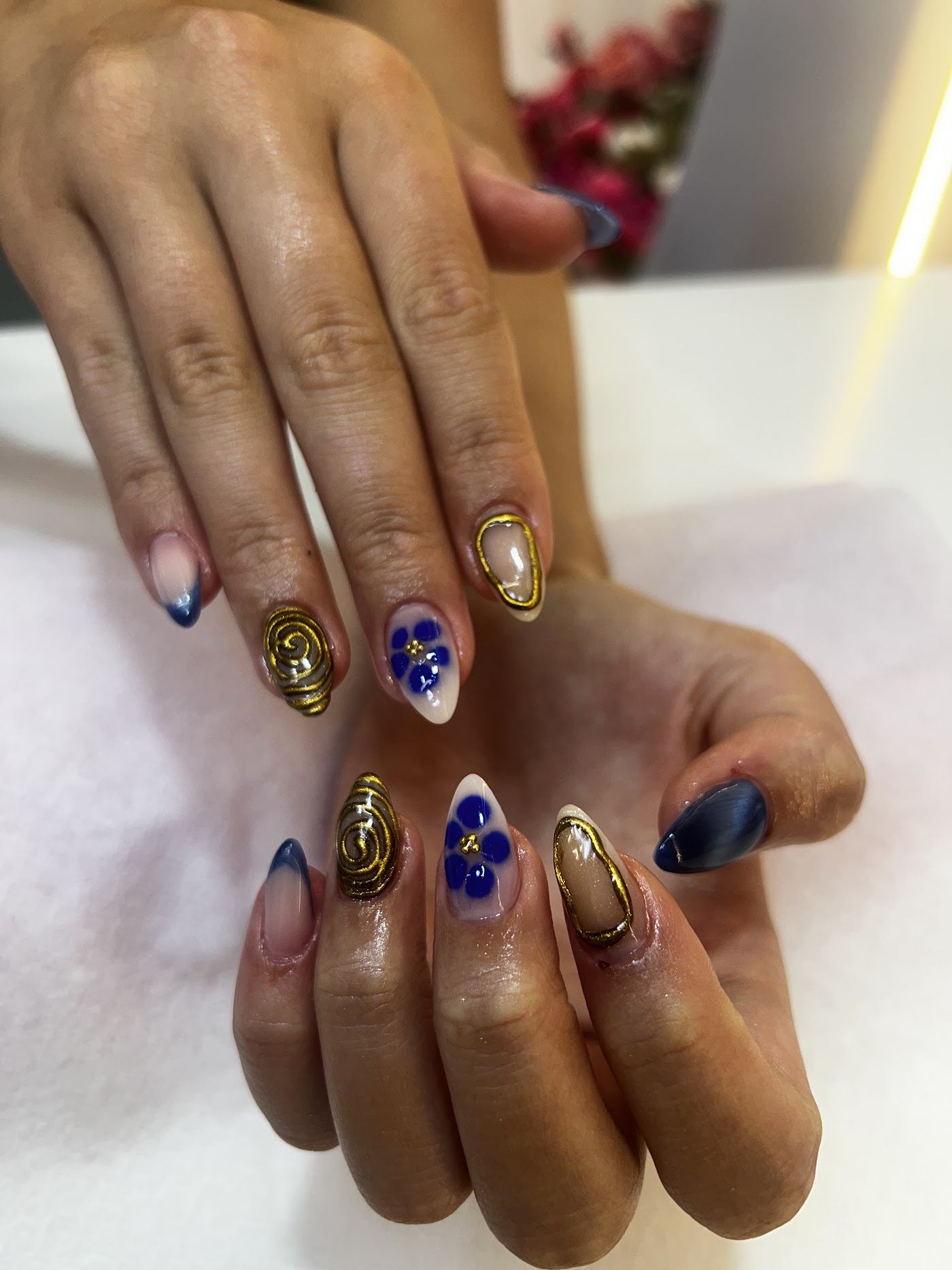 Nail art with gold chrome swirls and blue florals
