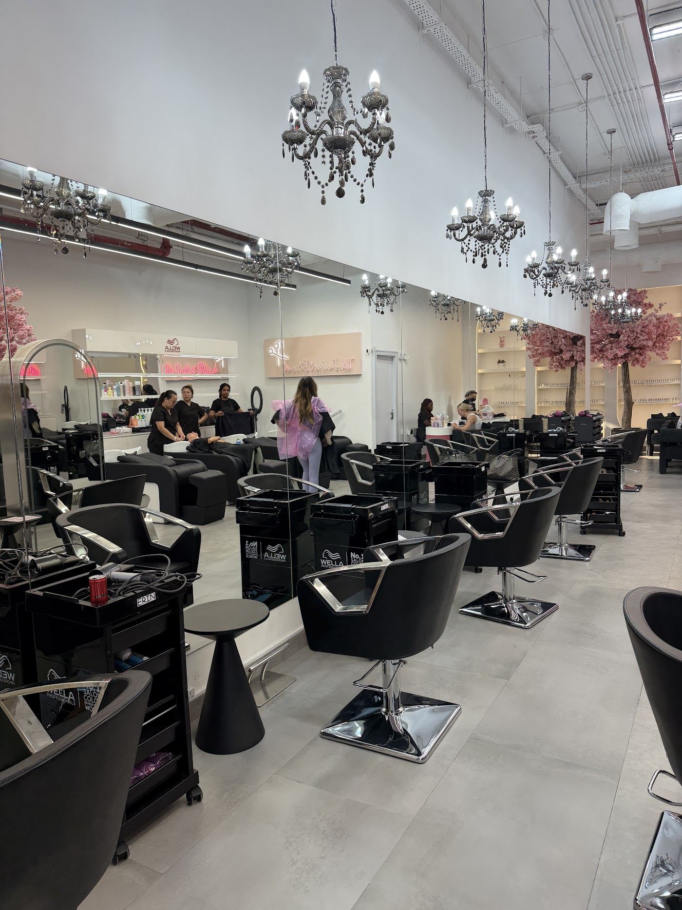 Inside The Perfect Blend salon in JVC: black styling chairs, chrome chandeliers and pink blossom trees